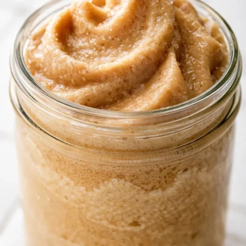 A tall glass of frozen whipped coffee with a creamy, frothy top and a straw, showing rich brown color and smooth texture.