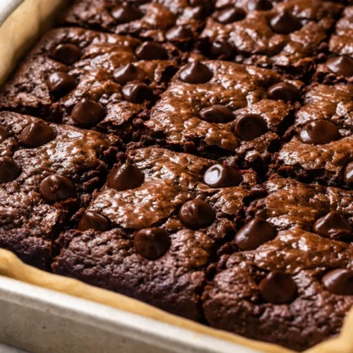 Moist, fudgy healthy banana brownies with dark chocolate chips, golden edges, and a rich brownie texture on a white plate.