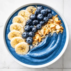 Blender mixing a thick, vibrant blue smoothie bowl with frozen blueberries and banana for a creamy texture.
