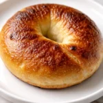 Golden brown cottage cheese flagels piled on a cooling rack, their chewy, bagel-like texture visible with everything bagel seasoning on top.