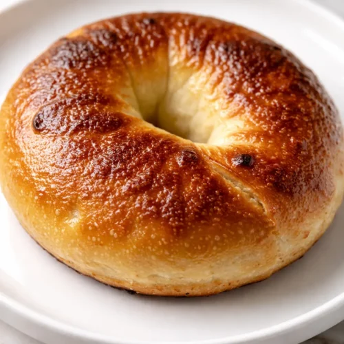Golden brown cottage cheese flagels piled on a cooling rack, their chewy, bagel-like texture visible with everything bagel seasoning on top.