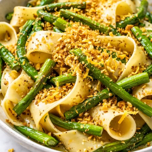 Creamy garlic scape pasta with vibrant green scapes and shaved Parmesan, glistening with olive oil.