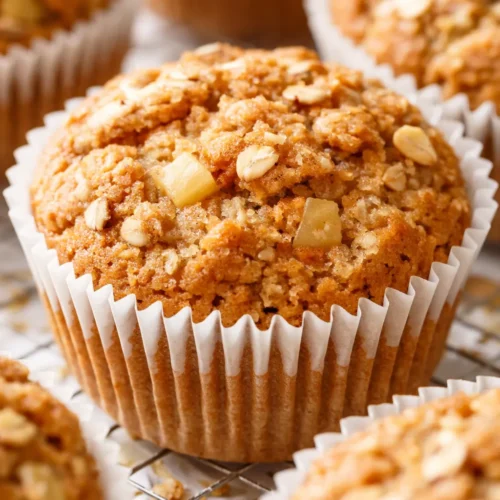 Golden brown healthy apple cinnamon oat muffins with visible oat flakes and tender crumb, sitting on a cooling rack