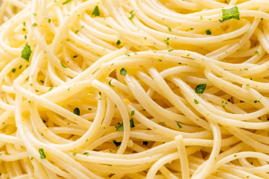 Bright lemon capellini salad with al dente pasta, fresh herbs, and cherry tomatoes in a white bowl, drizzled with tangy dressing.