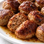 Golden brown Italian meatballs in rich tomato sauce, garnished with fresh parsley, revealing their tender, melt-in-your-mouth texture.