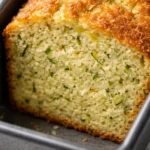 Moist lemon zucchini bread with a crunchy lemon sugar top, golden brown crust, and visible green zucchini flecks.