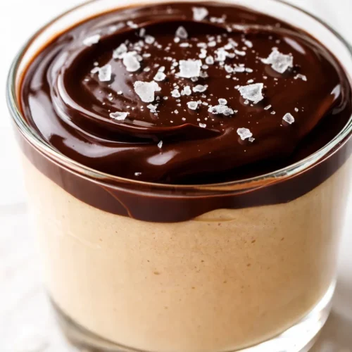 Decadent peanut butter mousse with chocolate ganache, silky texture, glossy dark chocolate drip, garnished with crushed peanuts.