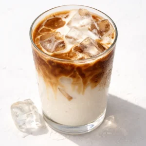 Pouring cold milk over ice in a glass for a homemade iced vanilla latte that costs 80 cents.