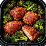 Crispy air fryer chicken pieces and mixed vegetables in a single layer inside the air fryer basket, with golden edges and caramelizing glaze.