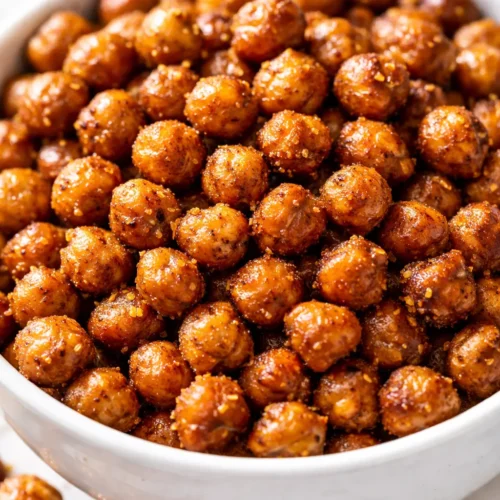 Golden brown air fryer crispy chickpeas piled in a bowl, seasoned with spices and herbs, showcasing a crunchy texture.