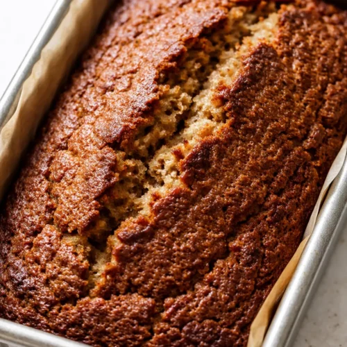 Ridiculously moist banana bread slice with golden crackly top, soft crumb, and dark brown edges.