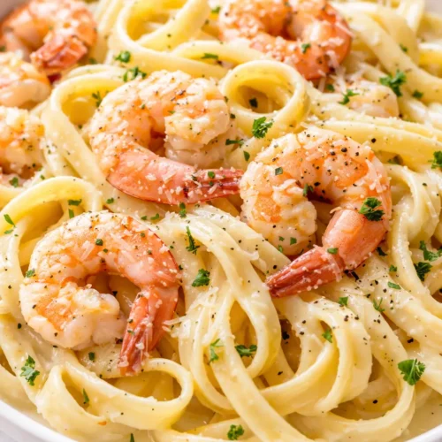 Creamy shrimp alfredo pasta with a silky, non-gloopy sauce coating fettuccine, garnished with shrimp, parsley, and Parmesan cheese.