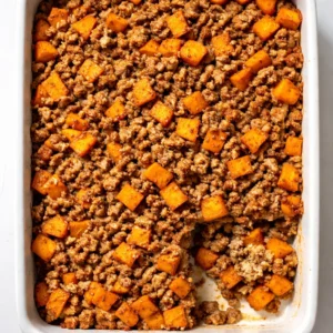 Browning lean ground turkey with diced onions in a skillet for a healthy ground turkey sweet potato bake.