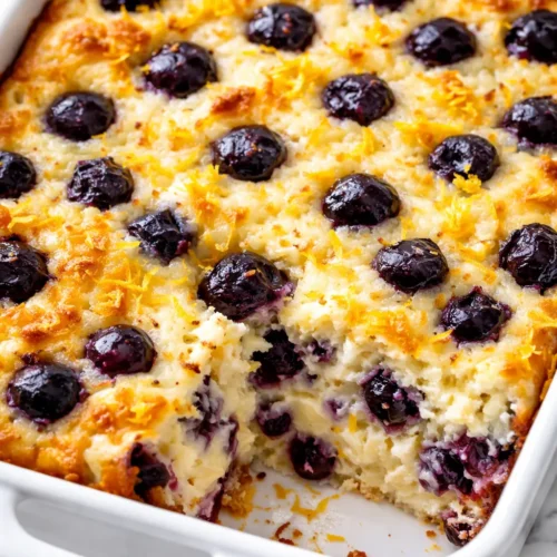 Golden-brown high protein blueberry cottage cheese bake with juicy blueberries and creamy cottage cheese, served warm in a baking dish.