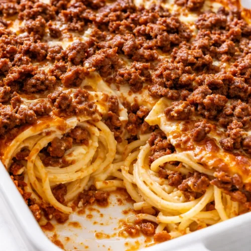 Layered million dollar spaghetti with creamy sauce, melted cheese, and tender pasta, baked to golden perfection.