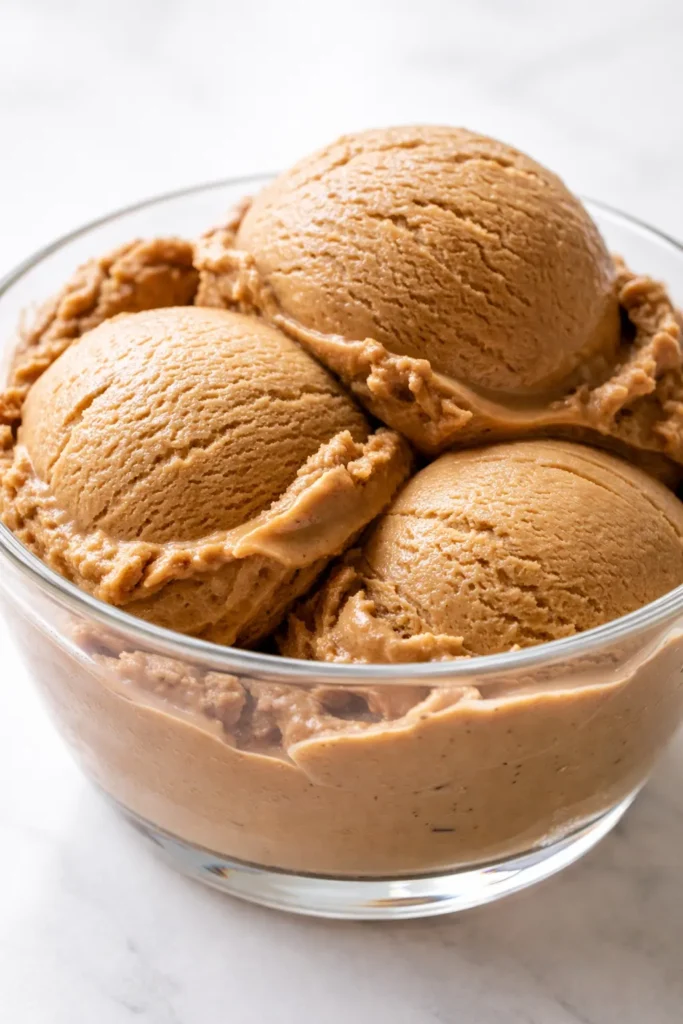 Scoop of no-churn bold coffee ice cream with silky texture and deep espresso color, garnished with coffee beans.