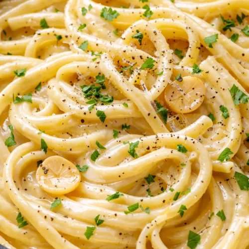 Silky twirled creamy garlic pasta in a luscious sauce that stays saucy, with visible creaminess and tender noodles.