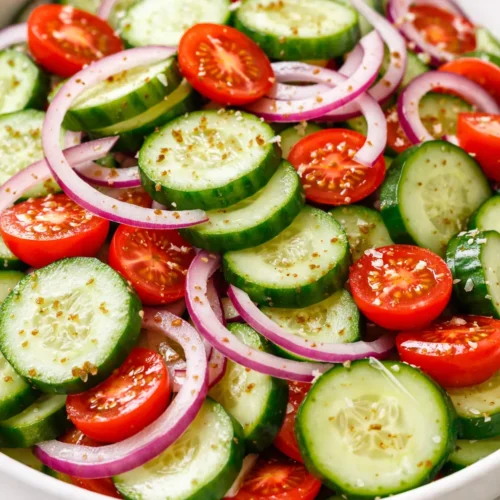 Spiced cucumber, onion, and tomato salad with crunchy fresh vegetables, colorful red and green, garnished with herbs and a tangy dressing.