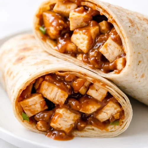 Fresh Thai peanut chicken wraps with crunchy vegetables, shredded carrots, and a drizzle of creamy peanut sauce, garnished with cilantro.