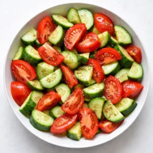 Diced cucumbers and tomatoes tossed with salt and herbs in a bowl to prevent sogginess and keep crunch.