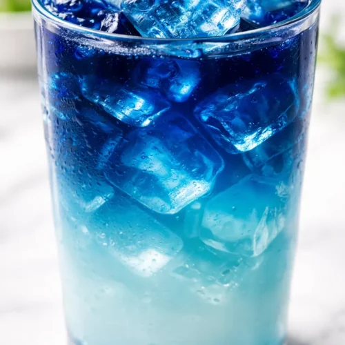 A vibrant ocean latte with a stunning natural gradient of blue, teal, and white, topped with a creamy foam.