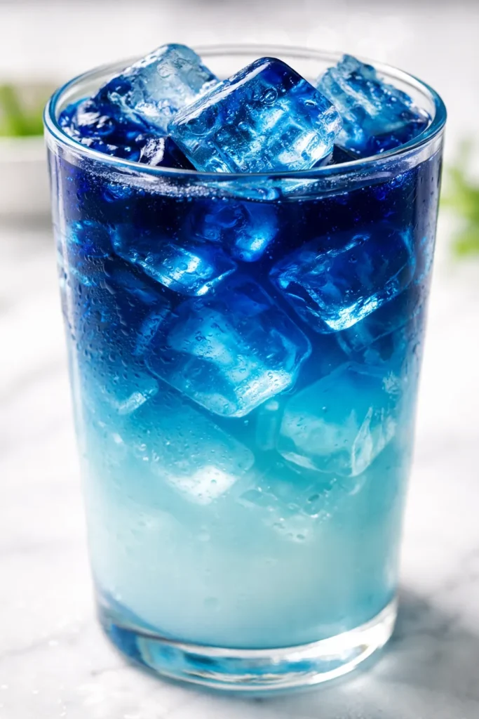 A vibrant ocean latte with a stunning natural gradient of blue, teal, and white, topped with a creamy foam.
