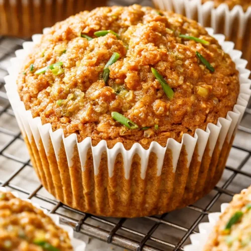 Moist zucchini oatmeal muffins with golden tops, chocolate chips, and walnut pieces on a plate