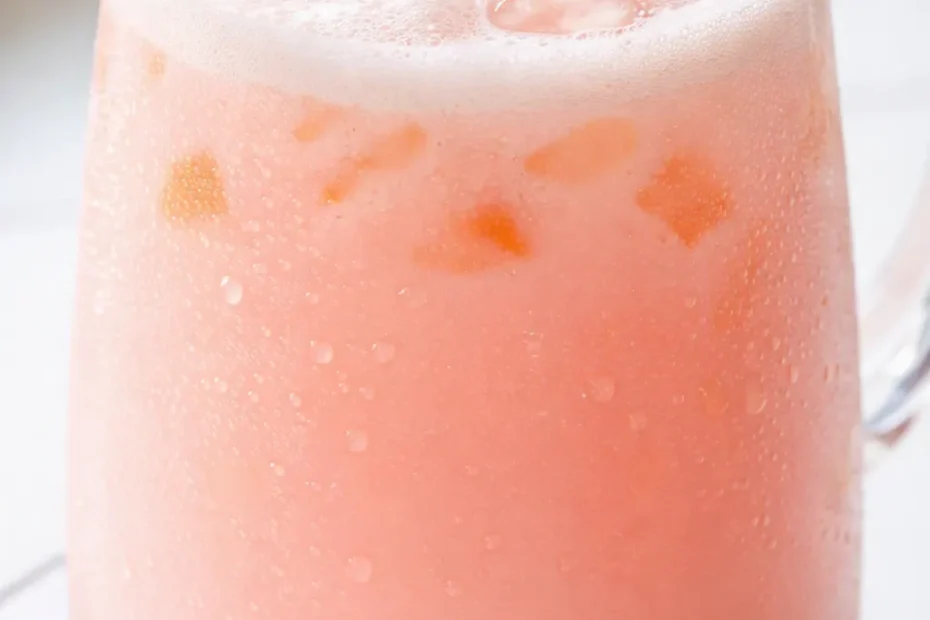 Vibrant pink copycat Starbucks Pink Drink in a tall glass with ice, strawberries, and a creamy coconut milk swirl.