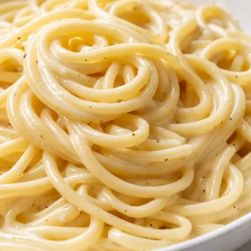 Creamy lemon pasta in a white bowl with glossy sauce, fresh parsley, and lemon zest, capturing a rich, restaurant-quality texture.