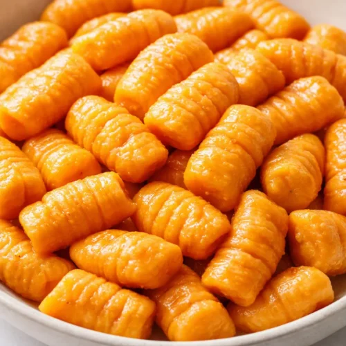 Healthy sweet potato gnocchi with golden-orange color, soft pillowy texture, and sage butter.