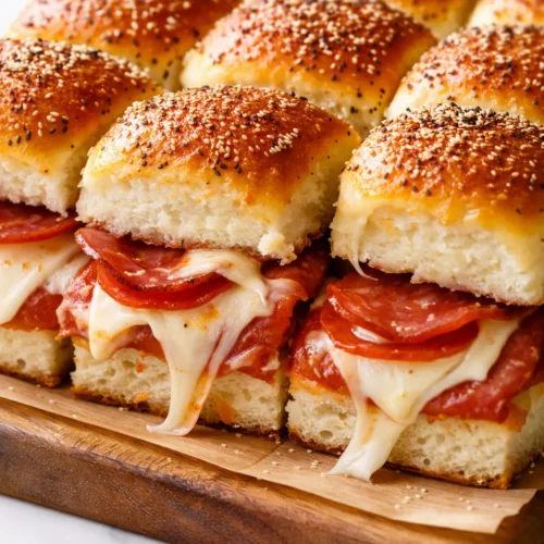 Pepperoni pizza sliders with golden toasted buns, bubbly melted mozzarella, and crisp pepperoni, fresh from the oven.