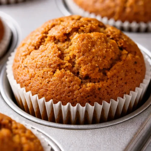 Two Starbucks pumpkin cream cheese muffins with golden-brown sugar tops and rich, creamy cheesecake swirl centers.